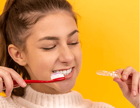 Woman brushing teeth with dental aligner